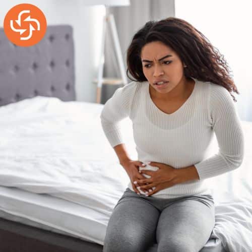 Women in white top suffering from stomach ache.