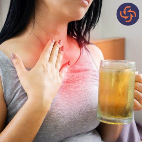 Woman with heartburn holding a cold drink.