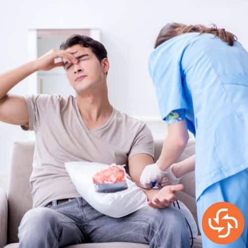 A nurse is taking blood sample of man in beige colour t-shirt.