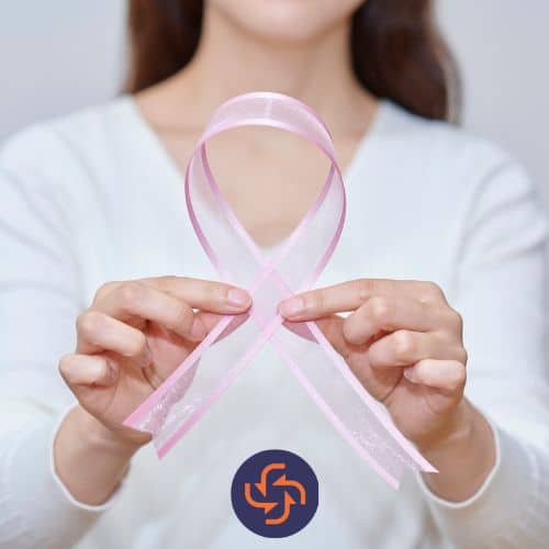 Woman holding a pink ribbon in her hands, symbolizing breast cancer awareness.