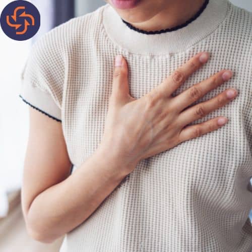 Person placing a hand on their chest, appearing to experience chest discomfort or pain.