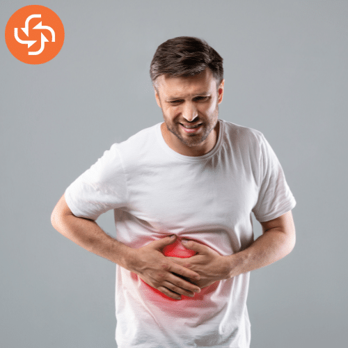 Middle-aged man in a white t-shirt holding his stomach with a painful expression, showing signs of abdominal pain or cramps.