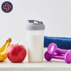 Protein shake bottle placed with an apple, banana, dumbbells, and a towel, representing fitness, nutrition, and healthy living.