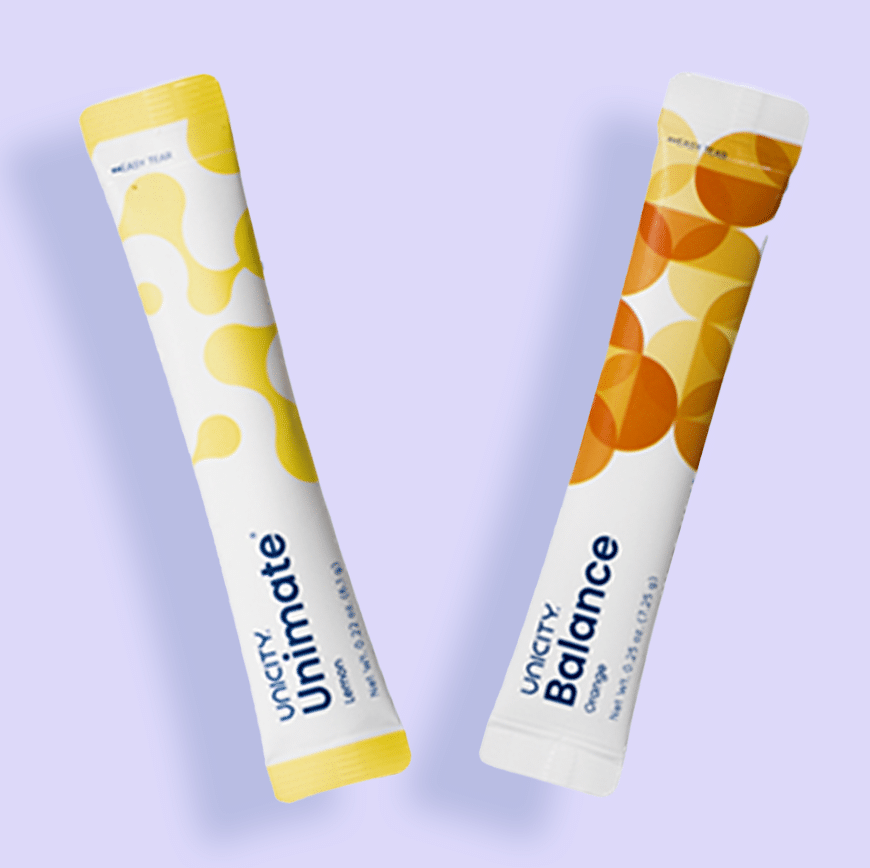 Two Unicity supplement sachets, one "Unimate Lemon" in yellow and one "Balance Orange" in white and orange, floating diagonally against a light purple background.
