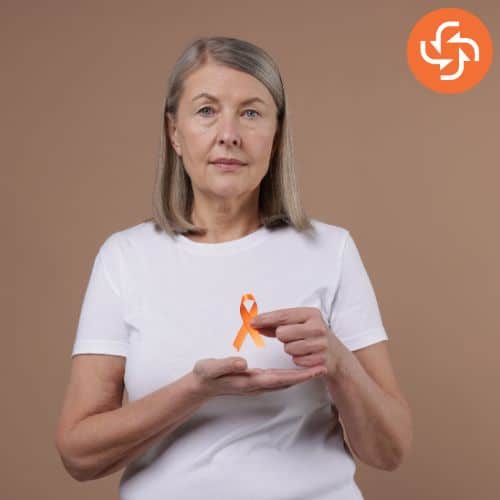 Middle-aged woman holding an orange awareness ribbon in her hands, symbolizing multiple sclerosis awareness and support.