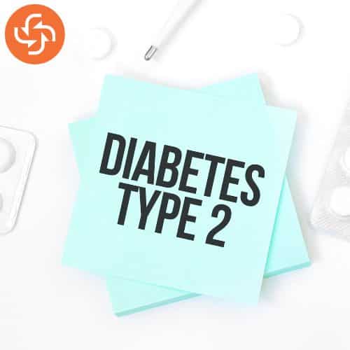 Note with the text 'Diabetes Type 2' placed on a desk with tablets and a pen, symbolizing type 2 diabetes awareness and management.