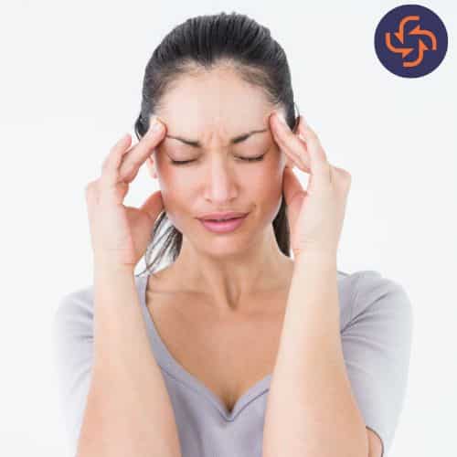 Young woman holding her temples and closing her eyes, experiencing a severe headache or migraine.